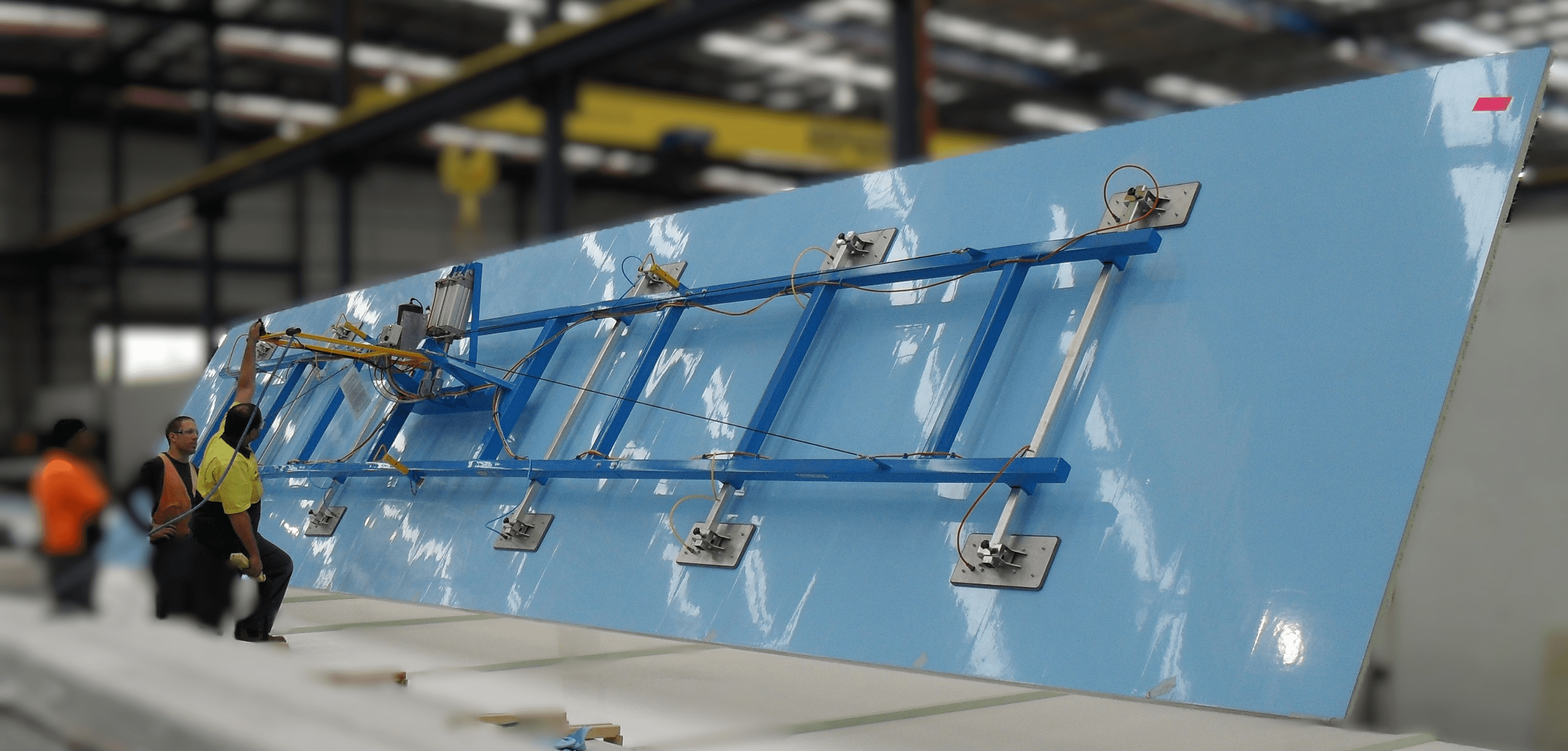 Vacuum lifting equipment in action - workers using blue vacuum lift system on large glass panel